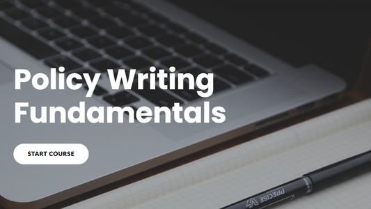 Laptop with 'Policy Writing Fundamentals' text and a pen on a desk