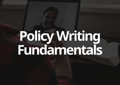 A dark promotional graphic with large white text reading 'Policy Writing Fundamentals' over a blurred scene of a person holding a pen and looking at a laptop.