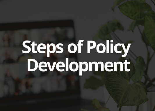 A dark-themed graphic with large white text reading 'Steps of Policy Development' over a blurred office scene with a laptop and green plant leaves.